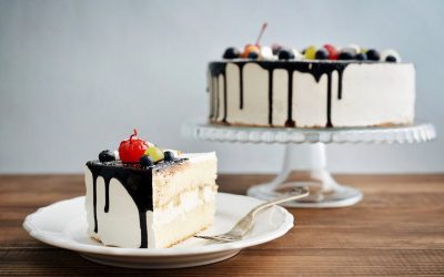 Fruit birthday cake  with cake slice over blue background